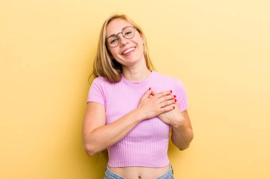 Genç sarışın kadın romantik, mutlu ve aşık, neşeyle gülümseyen ve kalbe yakın el ele tutuşan