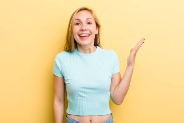 Genç, sarışın bir kadın mutlu, şaşkın ve neşeli, pozitif bir tavırla gülümsüyor, bir çözüm ya da fikir buluyor.