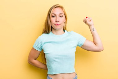 Genç sarışın kadın ciddi, güçlü ve asi hissediyor, yumruğunu kaldırıyor, protesto ediyor ya da devrim için savaşıyor.