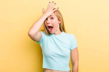 young adult  blonde woman raising palm to forehead thinking oops, after making a stupid mistake or remembering, feeling dumb