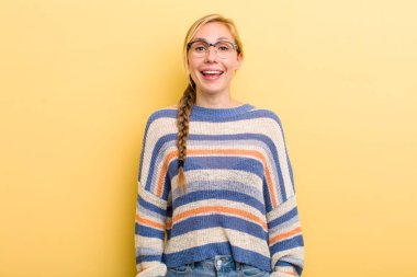 Genç sarışın kadın mutlu ve hoş bir şekilde şaşırmış görünüyor. Büyülenmiş ve şok olmuş bir ifadeyle heyecanlanıyor.