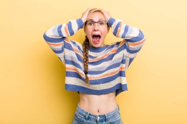 Genç, sarışın bir kadın el ele tutuşuyor, ağzı açık, son derece şanslı, şaşırmış, heyecanlı ve mutlu.