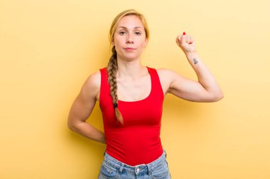 Genç sarışın kadın ciddi, güçlü ve asi hissediyor, yumruğunu kaldırıyor, protesto ediyor ya da devrim için savaşıyor.