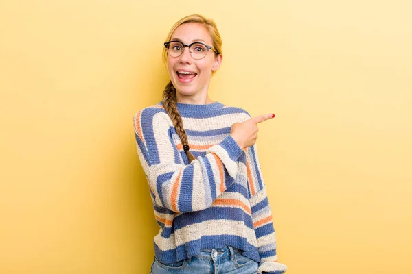 Young Adult Blonde Woman Looking Excited Surprised Pointing Side Upwards — Stockfoto