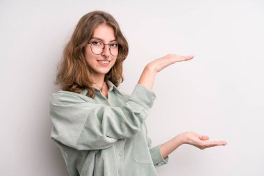 teenager young girl smiling, feeling happy, positive and satisfied, holding or showing object or concept on copy space
