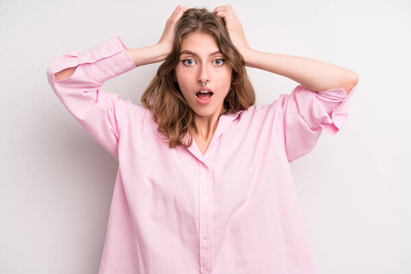 Девочка-подросток выглядит взволнованной и удивленной, с открытыми ртами, обеими руками на голове, чувствуя себя счастливой победительницей