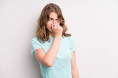 teenager young girl feeling disgusted, holding nose to avoid smelling a foul and unpleasant stench