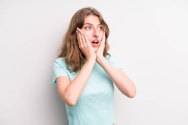 teenager young girl feeling happy, excited and surprised, looking to the side with both hands on face
