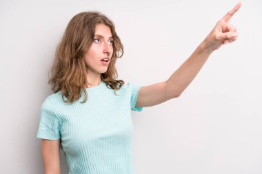 teenager young girl feeling shocked and surprised, pointing and looking upwards in awe with amazed, open-mouthed look