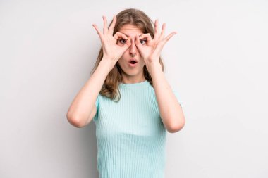 teenager young girl feeling shocked, amazed and surprised, holding glasses with astonished, disbelieving look