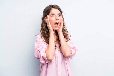 Genç ve güzel bir kadın mutlu, heyecanlı ve şaşırmış hissediyor. İki eli de havada bir tarafa bakıyor.