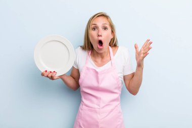 Sarışın, genç, yetişkin bir kadın elinde boş bir tabak tutuyor. Şef konsepti