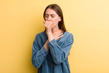 Sarı duvara yaslanmış genç ve güzel bir kadın.