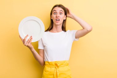 Genç, yetişkin, güzel şef kadın elinde boş bir tabak tutuyor.