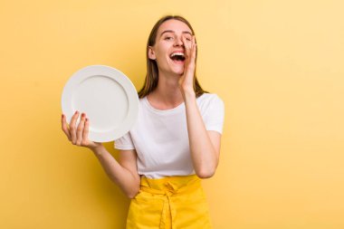 Genç, yetişkin, güzel şef kadın elinde boş bir tabak tutuyor.