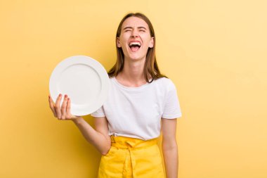 Genç, yetişkin, güzel şef kadın elinde boş bir tabak tutuyor.