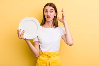 Genç, yetişkin, güzel şef kadın elinde boş bir tabak tutuyor.