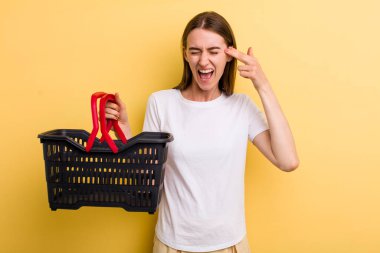 Genç ve güzel bir kadın elinde boş bir alışveriş sepeti tutuyor.