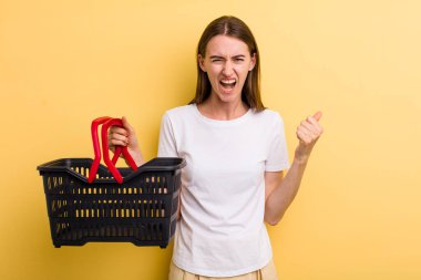 Genç ve güzel bir kadın elinde boş bir alışveriş sepeti tutuyor.