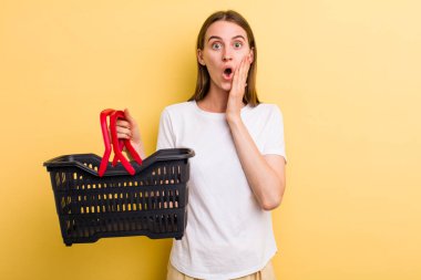 Genç ve güzel bir kadın elinde boş bir alışveriş sepeti tutuyor.