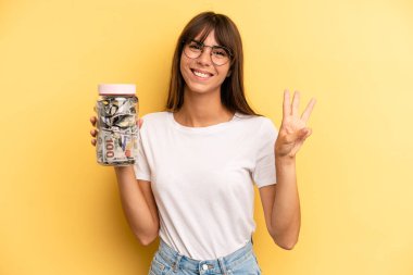 İspanyol kadın gülümsüyor ve arkadaş canlısı görünüyor, üç numarayı gösteriyor. kaydetme kavramı