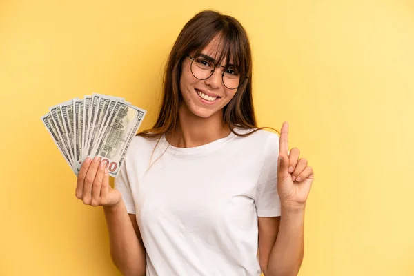 Hispanic Woman Smiling Looking Friendly Showing Number One Dollar Banknotes — Stockfoto