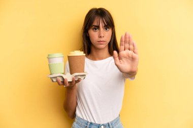looking serious showing open palm making stop gesture. take away coffees