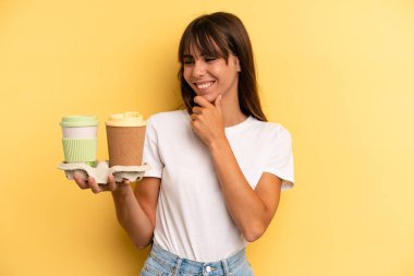 smiling with a happy, confident expression with hand on chin. take away coffees