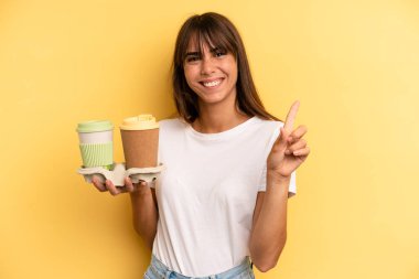 smiling and looking friendly, showing number one. take away coffees
