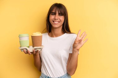 smiling and looking friendly, showing number four. take away coffees