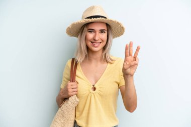 blonde woman smiling and looking friendly, showing number three. summer concept