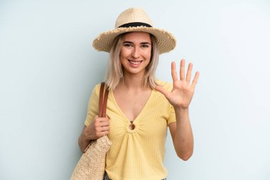 blonde woman smiling and looking friendly, showing number five. summer concept