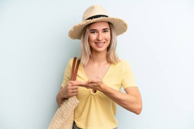 blonde woman smiling cheerfully, feeling happy and showing a concept. summer concept