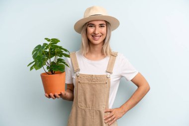 Sarışın kadın mutlu bir şekilde gülümsüyor, eli kalçasında ve kendinden emin. gardering konsepti