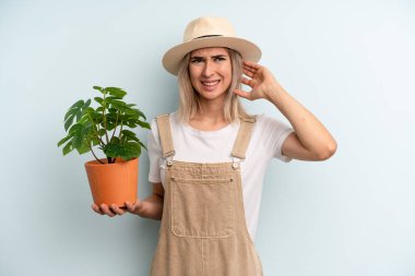 Sarışın kadın kendini stresli, endişeli ya da korkmuş hissediyor, elleri başının üstünde. gardering konsepti
