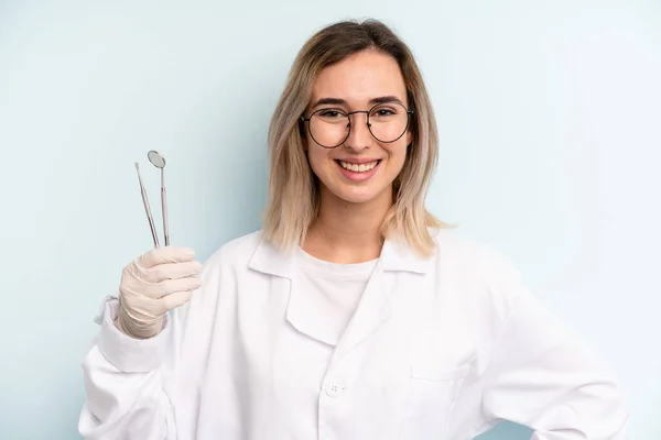 Blonde Vrouw Glimlacht Gelukkig Met Een Hand Heup Zelfverzekerd Tandartsconcept — Stockfoto