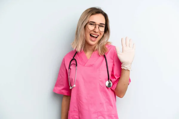 Blonde Woman Smiling Happily Waving Hand Welcoming Greeting You Nurse — 图库照片