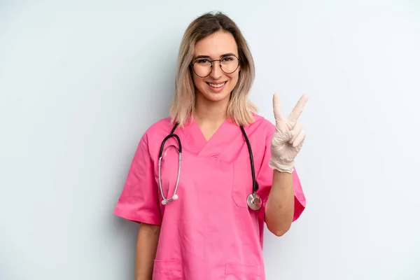 Blonde Woman Smiling Looking Friendly Showing Number Two Nurse Concept — Zdjęcie stockowe