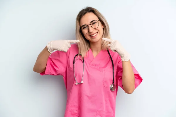 Blonde Woman Smiling Confidently Pointing Own Broad Smile Nurse Concept — Zdjęcie stockowe