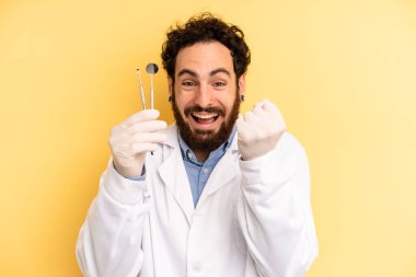 Genç adam şokta, gülüyor ve başarıyı kutluyor. dişçi kavramı