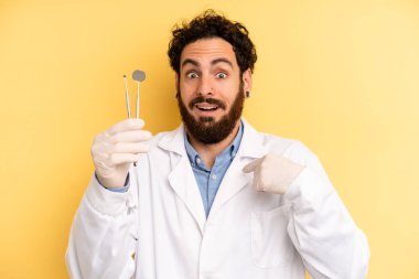 Genç adam mutlu hissediyor ve heyecanla kendini işaret ediyor. dişçi kavramı