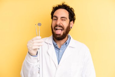 Neşeli ve asi tavırlı genç bir adam, şaka yapıyor ve dilini dışarı çıkarıyor. dişçi kavramı