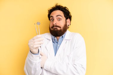 Genç adam omuz silkiyor, kafası karışık ve kararsız hissediyor. dişçi kavramı