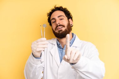 Genç adam gülümsüyor ve arkadaş canlısı görünüyor, bir numarayı gösteriyor. dişçi kavramı