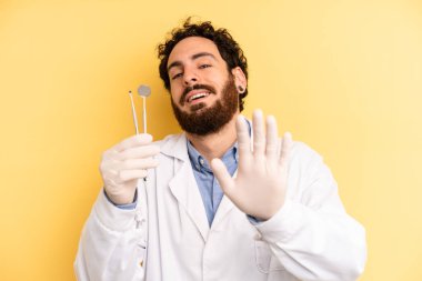 Genç adam mutlu bir şekilde gülümsüyor, el sallıyor, sizi selamlıyor ve selamlıyor. dişçi kavramı