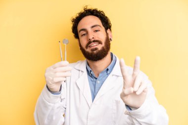 Genç adam gülümsüyor ve iki numarayı gösteriyor. dişçi kavramı