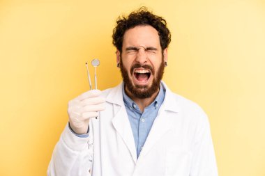 Genç adam agresif bir şekilde bağırıyor, çok kızgın görünüyor. dişçi kavramı