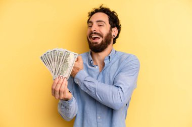 Genç adam kendini mutlu hissediyor ve bir meydan okumayla yüzleşiyor ya da kutluyor. Dolar banknotları konsepti
