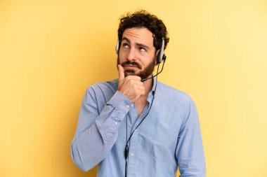 Genç adam düşünüyor, kuşkulu ve şaşkın hissediyor. tele pazarlamacı kavramı