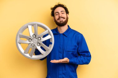 Genç adam neşeyle gülümsüyor, mutlu hissediyor ve bir konsept gösteriyor. araba mekaniği kavramı